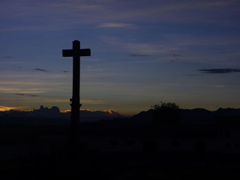 Silhouette cross against sky during sunset