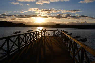 Pier over sea against sky during sunset