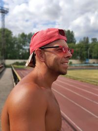 Side view of young man looking away against sky