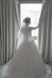 Woman standing on field seen through window. girl wedding dress 