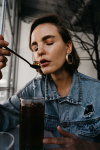 Close-up portrait of a young woman drinking glass