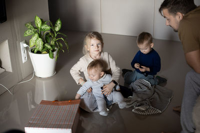 Three kids and dad play on the floor at home