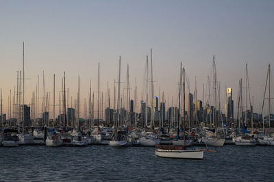 Sailboats moored in sea against clear sky during sunset