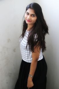 Portrait of a smiling young woman standing against wall