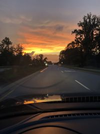 Road against sky during sunset seen through car windshield