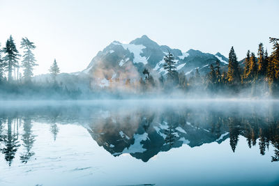 Scenic view of lake by snowcapped mountains against sky