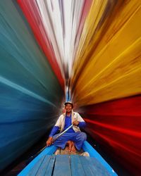 Portrait of woman sitting on blue umbrella