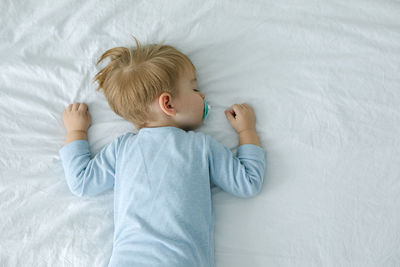 High angle view of baby boy sleeping on bed at home