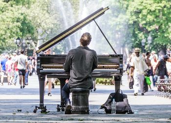 Man playing piano while sitting on city street