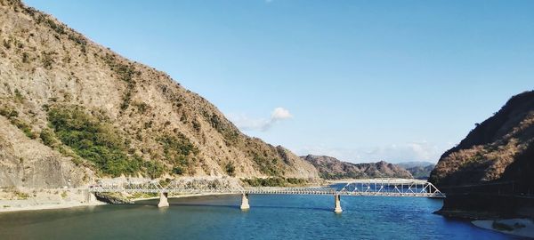 Scenic view of bridge over mountains against blue sky