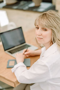 Portrait of young woman with laptop and cup of coffee