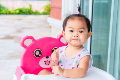 Portrait of cute baby girl sitting on high chair