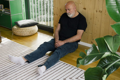 Upset man sitting down near wooden wall at home