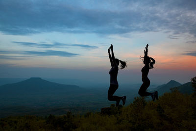 Silhouette people on mountain against sky during sunset