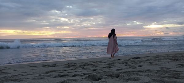 Rear view of woman on beach during sunset