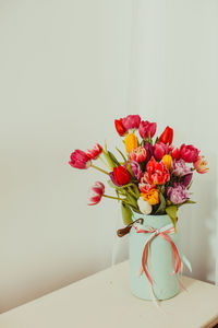 Close-up of red flower vase on table against wall