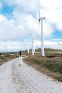 Rear view of woman walking on field against sky