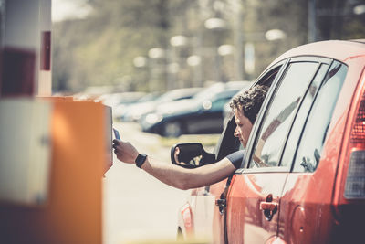 Man holding accessing credit on machine from car window