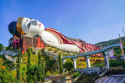 Low angle view of amusement park against clear blue sky