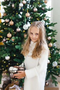 Portrait of girl standing by christmas tree