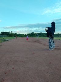 Rear view of woman photographing on land against sky