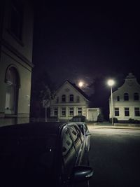 Cars on street against illuminated buildings in city at night