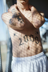 Midsection of shirtless man with tattoo