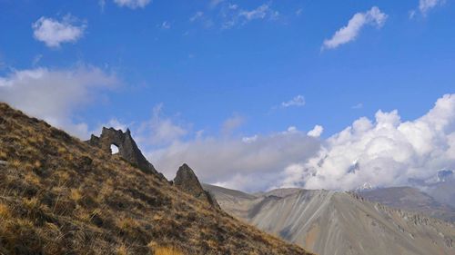 Scenic view of mountains against cloudy sky on sunny day