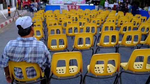 Rear view of people sitting on street in city