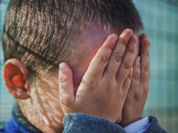 Boy with hands covering face