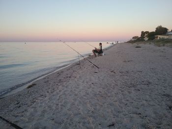 Man on beach against sky during sunset