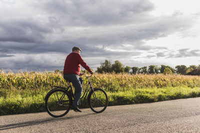 Senior man riding bicycle on country lane