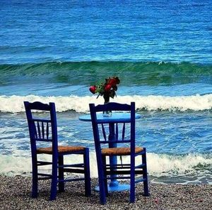 Deck chairs on beach against sky