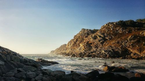 Scenic view of rocky coast against clear sky