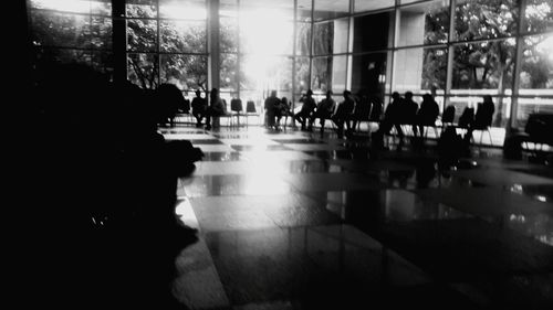 Silhouette people walking on tiled floor by window