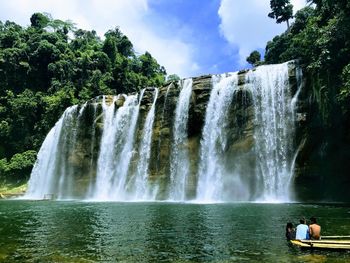 People sitting against waterfall