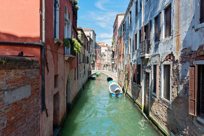 Rear view of man on canal amidst buildings in city