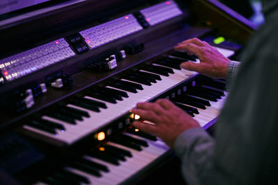 Cropped wrinkled hands of musician playing piano