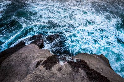 High angle view of waves splashing on rocks