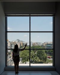 Rear view of woman looking through window