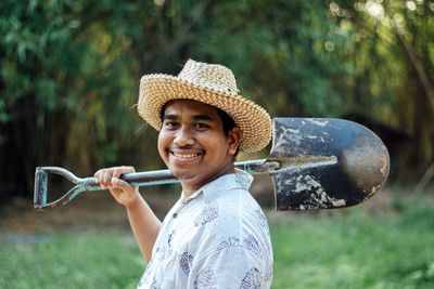 Portrait of smiling man wearing hat standing against plants