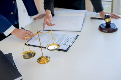 Midsection of lawyer guiding businessman during contract form filling on desk