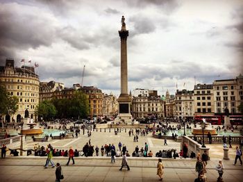 Tourists in front of building against cloudy sky