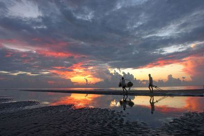 Scenic view of lake against dramatic sky during sunset