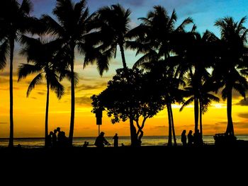 Silhouette palm trees on beach against sky during sunset