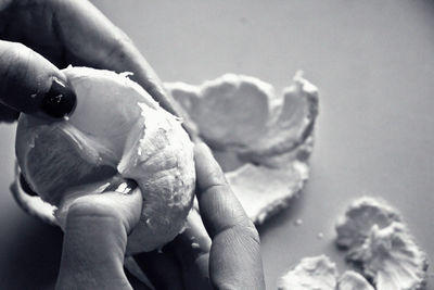 Cropped hands of woman peeling orange fruit at home