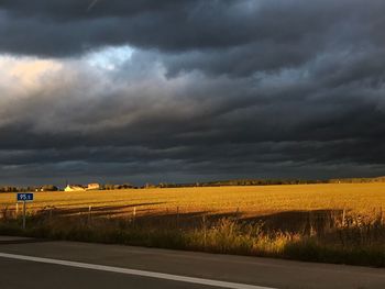 Scenic view of field against dramatic sky