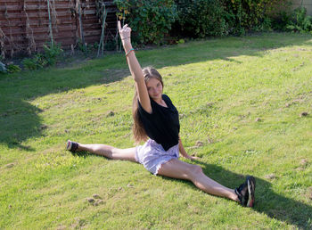 Teenage girl doing acrobatic exercises on a green lawn, sport, generation z,