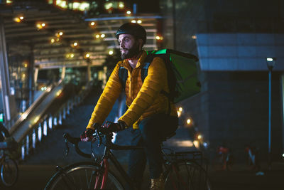 Man riding bicycle on illuminated city at night