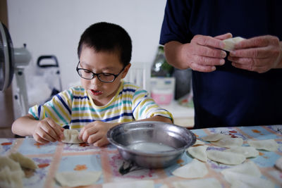 Boy preparing food by father on kitchen